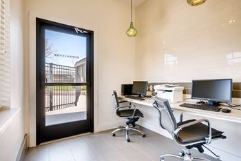 A modern office with a view of a black gate and trees outside.